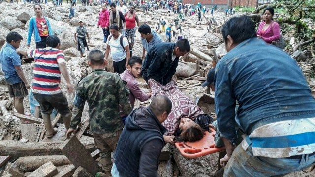 снимка : Handout picture released by the Colombian Army press office showing people helping to carry a woman after mudslides following heavy rains, in Mocoa, Putumayo department, on April 1, 2017.